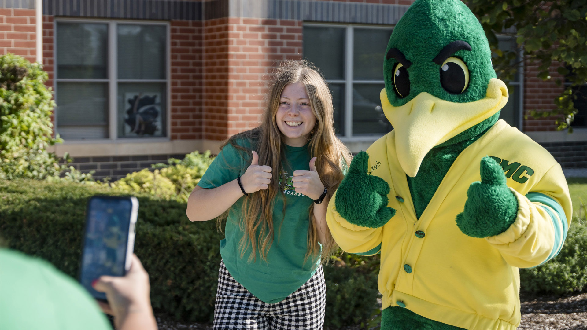 Student taking photo with Ronnie Roadrunner .